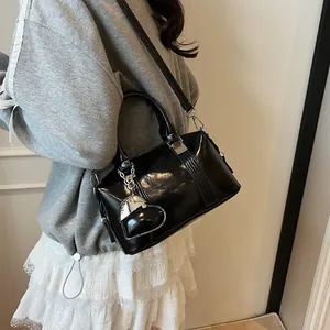 Glossy black Boston handbag for women with silver heart pendant and adjustable strap