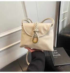 Detail of off-white shoulder bag featuring woven knot and gold U-shaped metal buckle