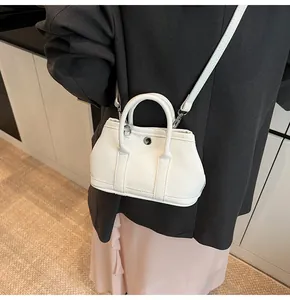 Primer plano de un bolso bandolera blanco con textura de grano y botón plateado en modelo