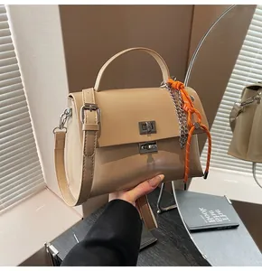Detail of soft apricot faux leather bag with metal twist lock and woven charm