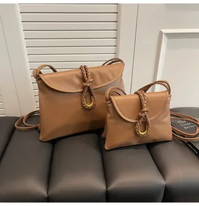 Close-up of brown faux leather bags with braided flap and golden metal buckle details