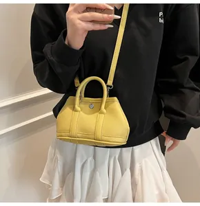 Detalle de cuero amarillo con textura de lichi y cierre giratorio plateado del mini bolso