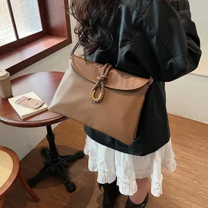 Classic brown leather tote bag with braided handle and gold buckle in a cafe setting