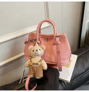 Detalle del bolso bandolera de cuero rosa con un lindo colgante de oso de peluche