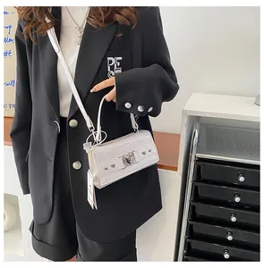 Détail du mini sac blanc à motif crocodile avec une grande boucle coeur argentée et rivets