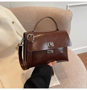 Detailed view of deep brown vintage handbag with polished texture and silver metal twist lock