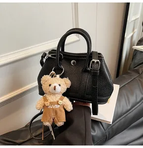 Detalle de bolso negro en cuero granulado con tachuelas plateadas y colgante de osito