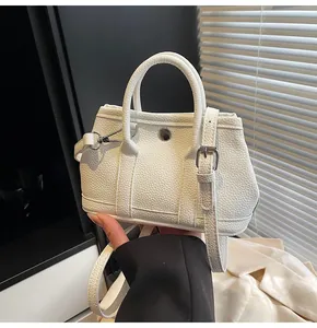 Detalle de mini bolso blanco en cuero con grabado lichi, hebilla plateada y doble asa