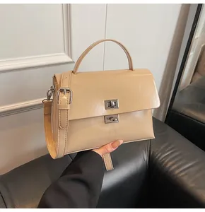 Detail of beige messenger bag showing silver turn-lock and polished leather texture