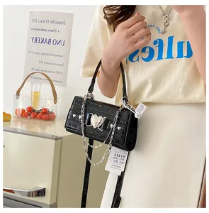 Détail du mini sac carré noir avec texture crocodile et boucle en forme de cœur
