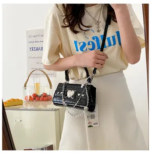 Détail du mini sac à main motif crocodile avec cœur argenté et chaîne décorative