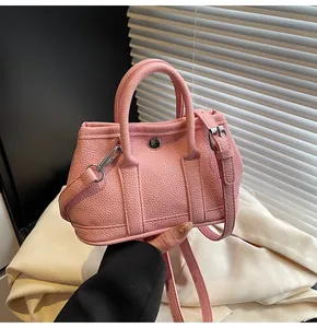 Primer plano de mini bolso rosa de piel con grano de lichi, asas y hebilla metálica