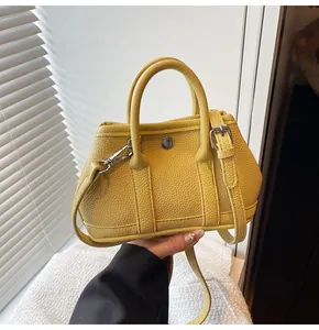 Detalle de bolso de cuero amarillo con textura granulada y hebilla redonda de metal plateado