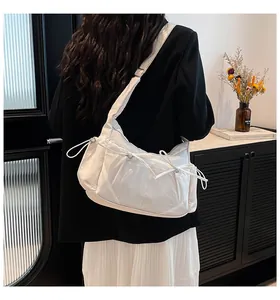 Détail du sac bandoulière blanc en nylon avec poches à cordon sur un modèle porté