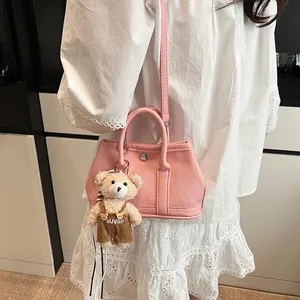 Bolso bandolera rosa con textura de lichi para mujer con adorno de osito y cierre plata