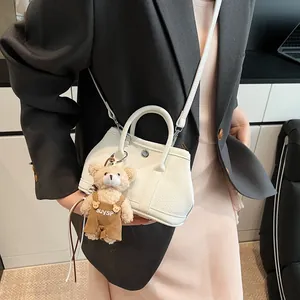 Bolso de mano blanco en cuero lichi con hebilla de metal y colgante de oso en bandolera