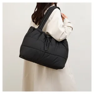 Detalle de bolso tote acolchado negro con cordón ajustable lateral y textura acolchada