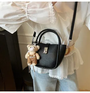 Détail du sac seau noir en cuir avec fermoir argenté et charmant petit ours en peluche