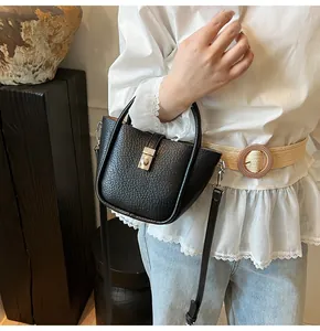 Détail d'un sac seau en cuir noir grainé avec boucle en métal argenté et doubles poignées