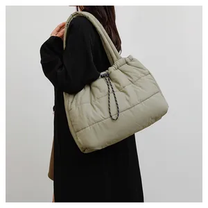 Detalle del bolso acolchado verde salvia con cordones decorativos en la modelo
