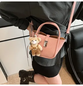 Gros plan du sac seau en cuir rose avec un ours en peluche marron et un fermoir en métal