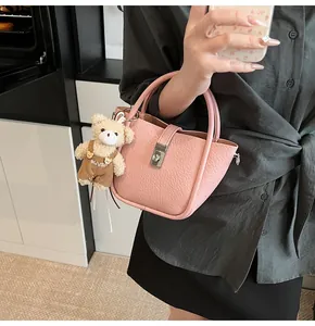 Détail du sac seau en cuir rose avec fermoir argenté et petit pendentif ours mignon