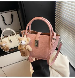 Détail du sac seau rose texturé avec fermoir métallique et breloque ours en peluche
