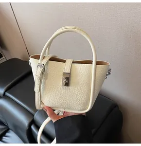 Détail du sac seau en cuir grainé blanc crème avec fermoir rotatif argenté et poignée
