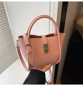 Gros plan du fermoir rotatif argenté et du cuir grainé de ce sac seau rose pastel
