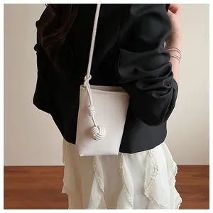 Detail of off-white drawstring bucket bag with litchi leather texture and thick rope strap