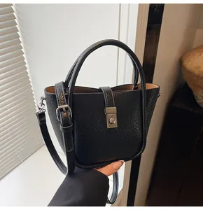 Détail du sac seau en cuir noir grainé avec boucle argentée et poignée arrondie
