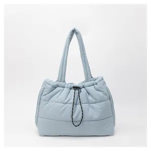 Detalle del bolso tote acolchado azul claro con cierre de cordón y cuerda texturizada