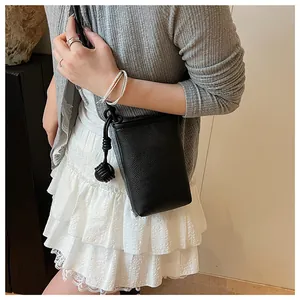 Close-up of black litchi grain leather phone bag with a stylish side knot detail