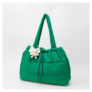 Detalle del bolso tote acolchado verde con cordón y colgante de peluche blanco