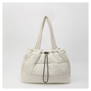 Vista detallada del bolso tote acolchado crema con textura y cierre de cordón ajustable