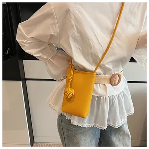 Detail of yellow pebbled leather mini crossbody bag with matching decorative knot charm