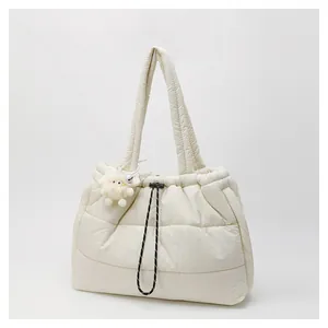 Detalle de bolso tote acolchado color crema con colgante de peluche y cordón decorativo