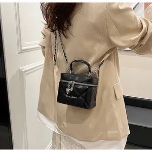 Detail der schwarzen gesteppten Mini-Tasche mit Kette und Herz-Anhänger auf beigem Blazer