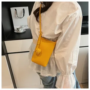 Mini yellow lychee leather crossbody bag with knot shoulder strap detail shown on model
