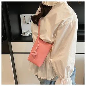 Detail of pink lychee texture PU leather phone bag with stylish knotted shoulder strap