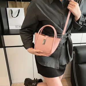 Sac seau rose texture litchi avec boucle argentée et bandoulière porté par un mannequin