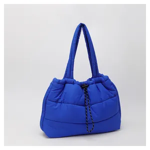 Detalle de bolso tote acolchado azul real con cordón decorativo y correas suaves