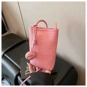 Detail of pink pebbled leather mini crossbody phone bag with decorative knot ball charm