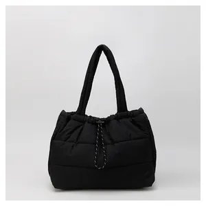 Detalle del bolso acolchado negro mostrando tela impermeable y cierre con cordón