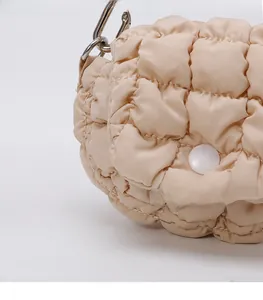Detail of beige quilted bubble fabric bag showing silver hook and round button closure