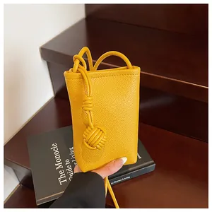 Detailed view of yellow litchi texture on vertical phone bag with woven leather ball knot