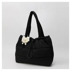 Primer plano del bolso tote acolchado negro con detalle de amuleto de lazo blanco suave