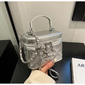 Detail der silbernen gesteppten Handtasche mit Metallkette und Herzanhänger