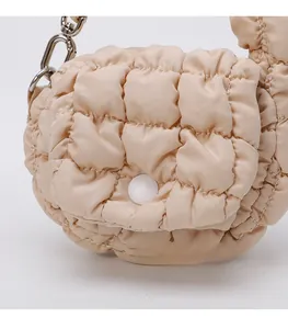 Detail of beige quilted mini cloud bag featuring a pearl button and metal chain strap