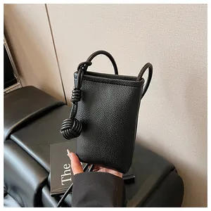 Detail of black mini crossbody phone bag in pebble leather with woven knot charm